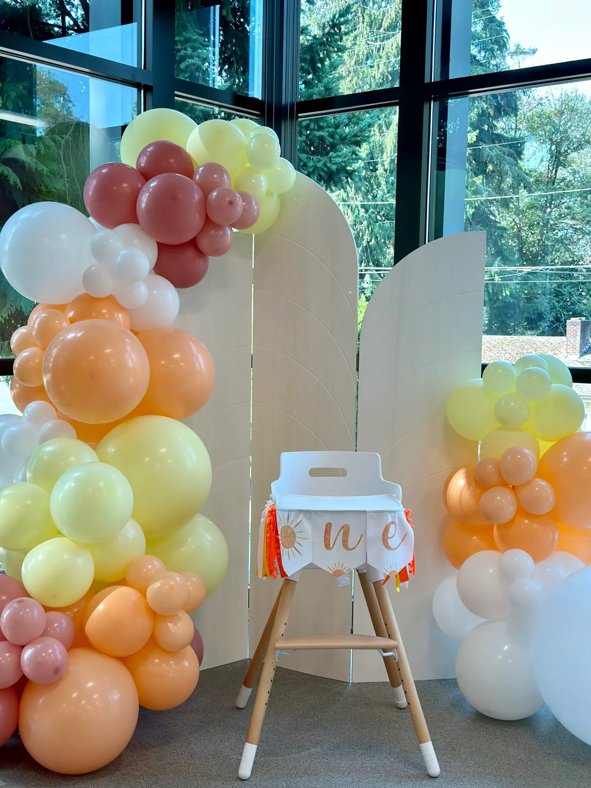 A high chair is surrounded by balloons for a baby 's first birthday.