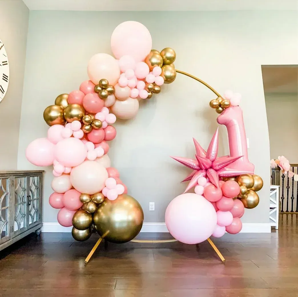 A room filled with pink and gold balloons and a clock on the wall.
