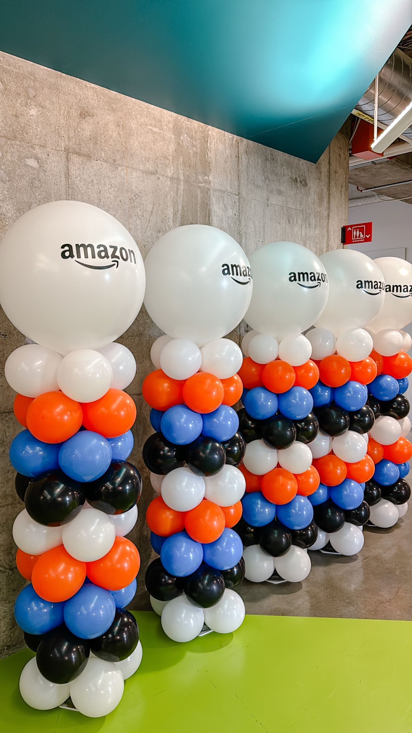 Row of Amazon-branded balloon columns with orange, blue, black, and white balloons.