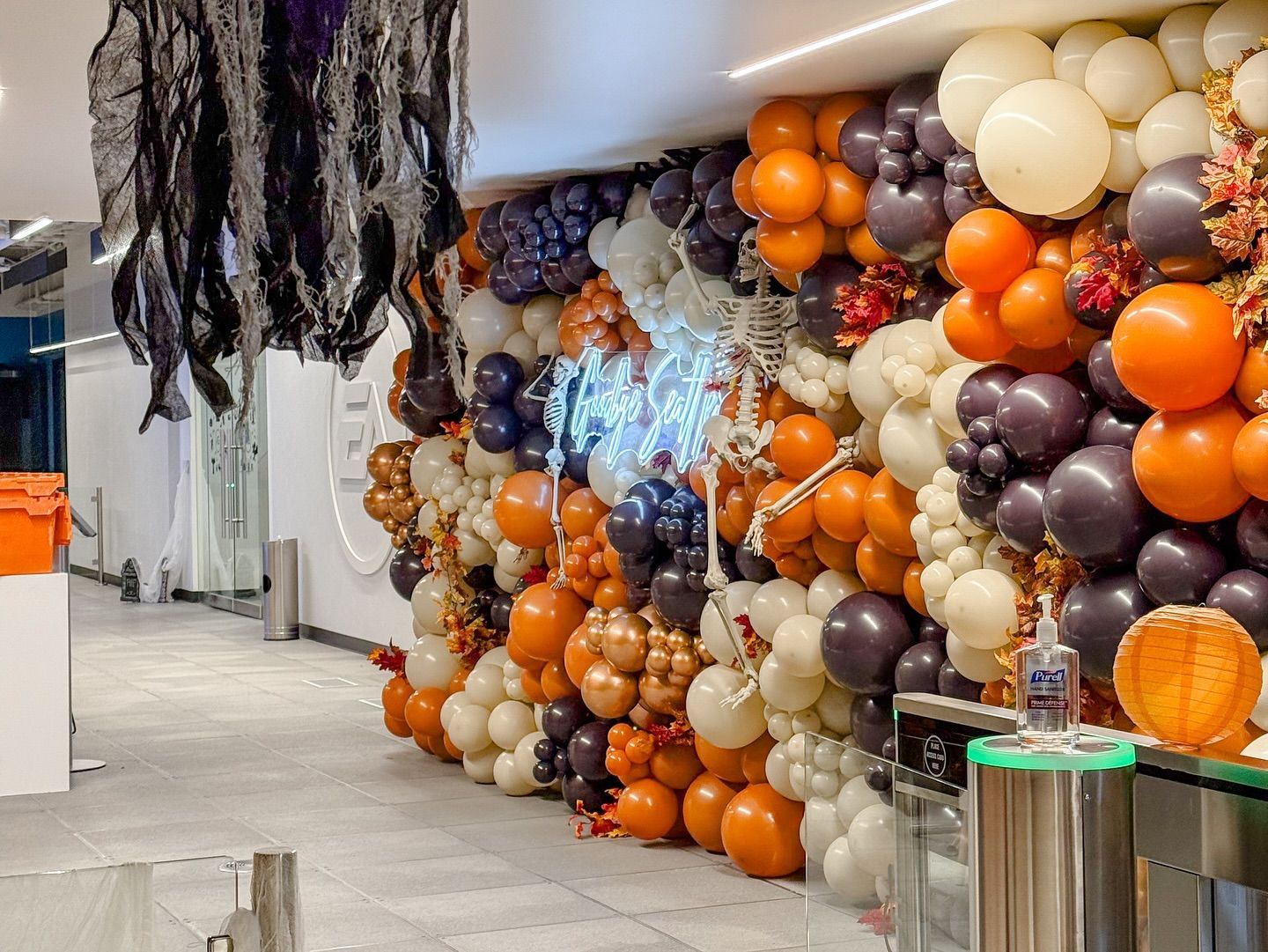 A wall of balloons decorated for halloween in a hallway.
