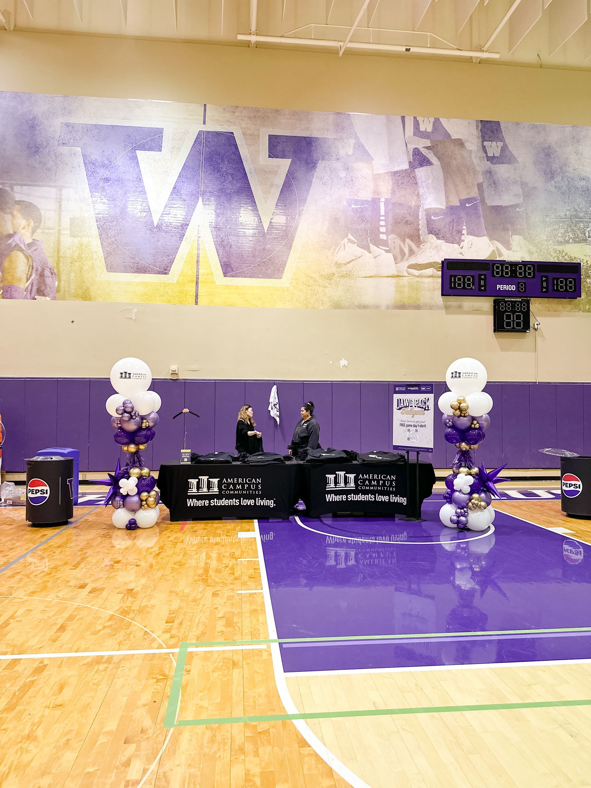 A basketball court decorated with balloons and a large w on the wall.