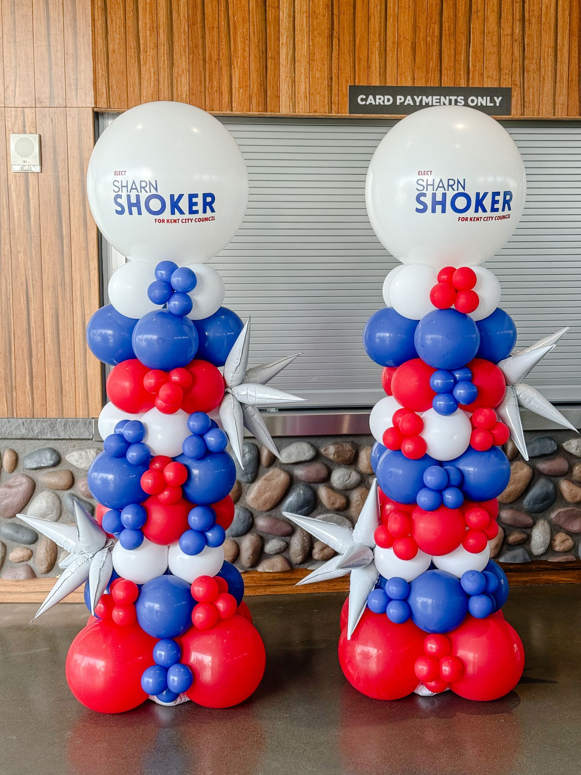 Two patriotic balloon columns with red, white, and blue balloons, featuring a