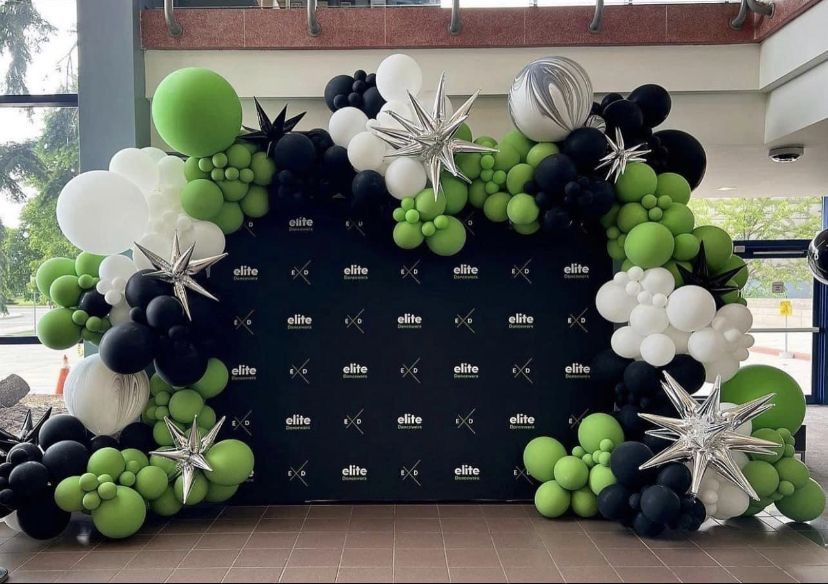A wall covered in black , white and green balloons