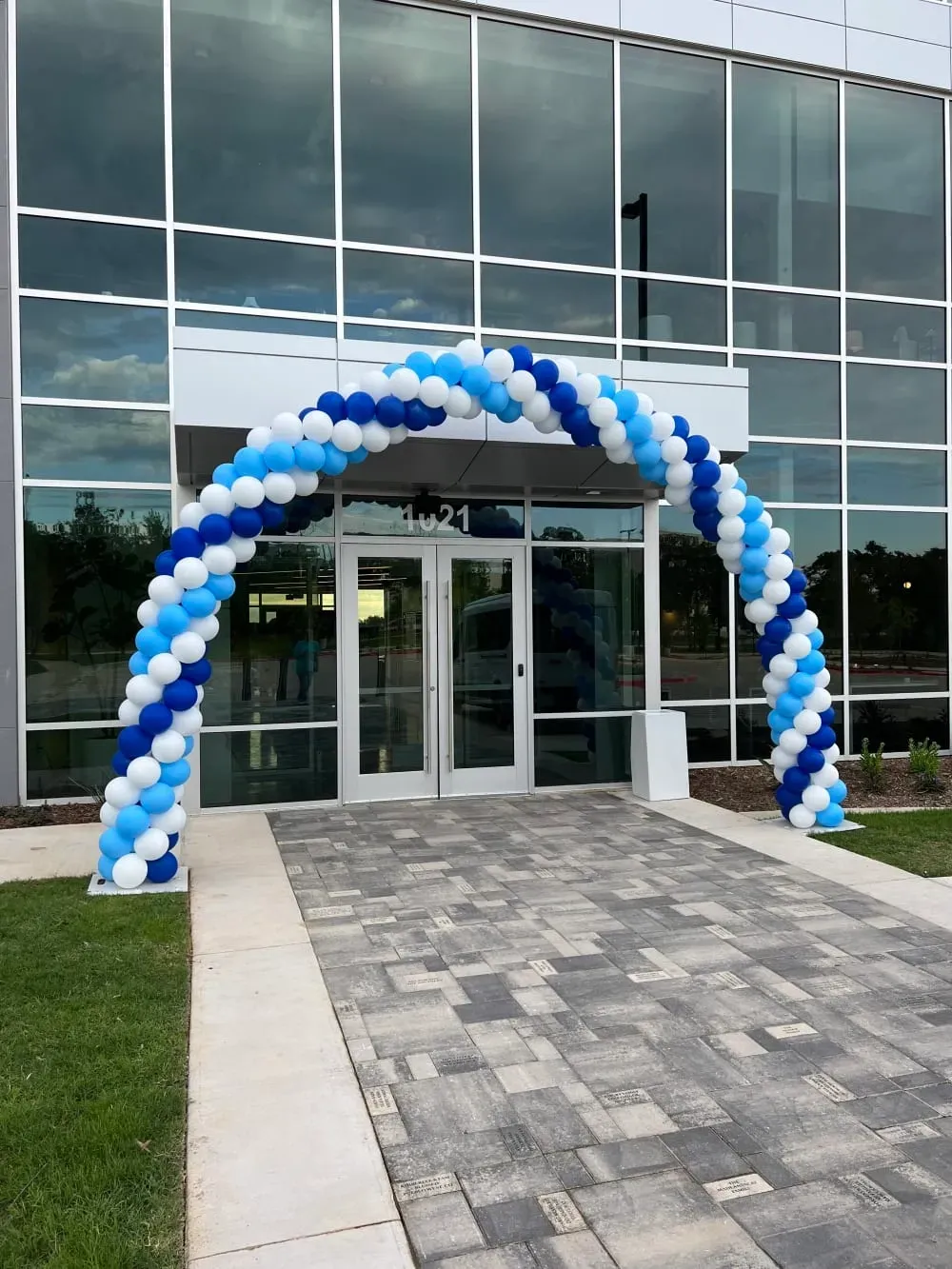A blue and white balloon arch is in front of a building.