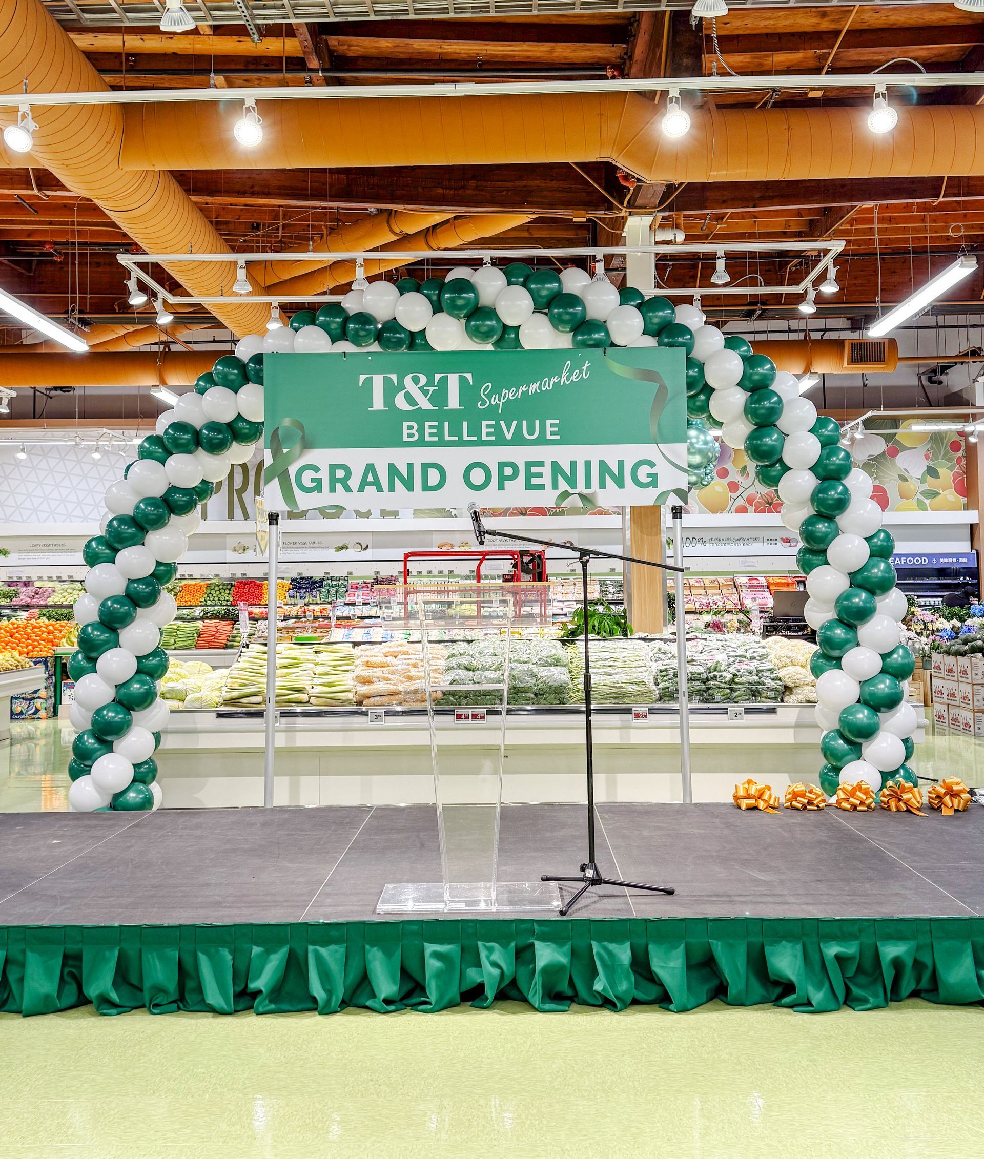 A stage with balloons and a sign that says grand opening