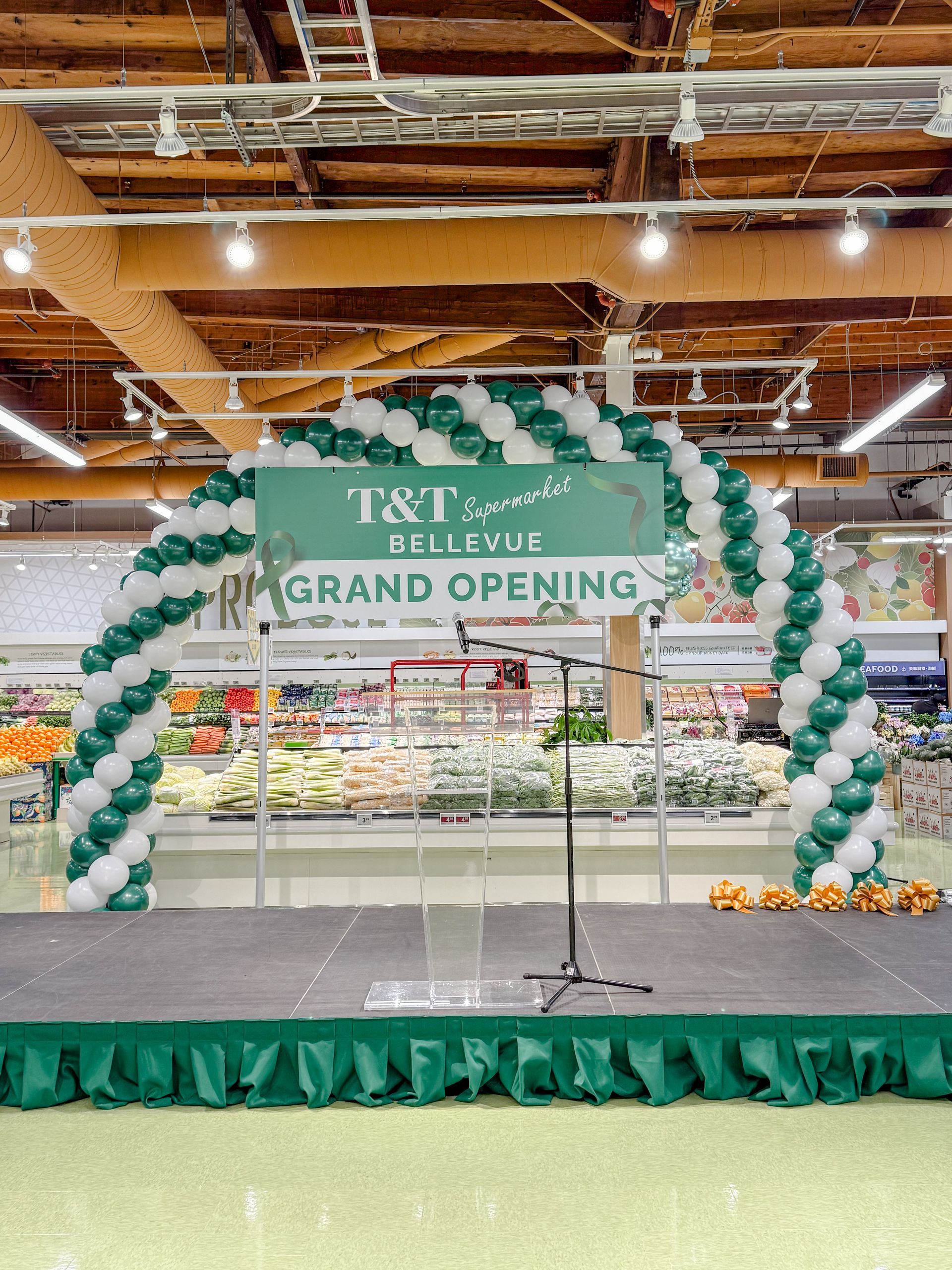 A stage with balloons and a sign that says `` grand opening '' in a grocery store.