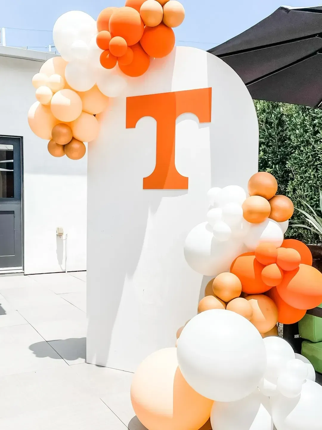 A white wall decorated with orange and white balloons and the letter t