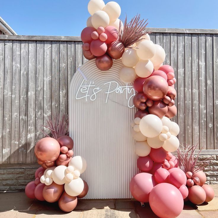 A sign that says let 's party is surrounded by balloons.