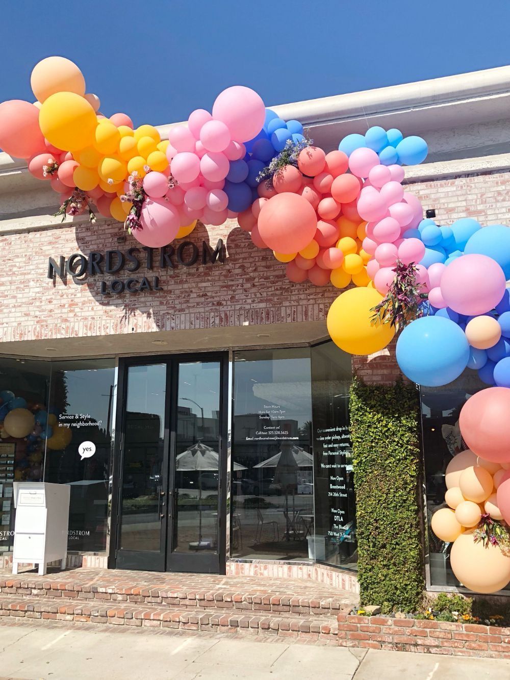 A store front decorated with colorful balloons and flowers
