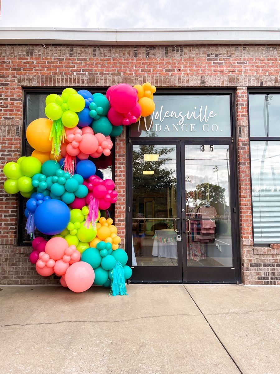 A bunch of colorful balloons are hanging in front of a brick building.
