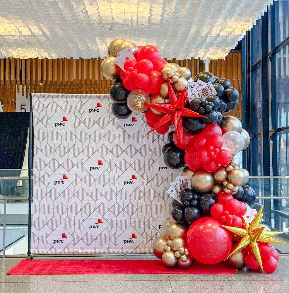 A bunch of red , black and gold balloons are sitting in front of a wall.
