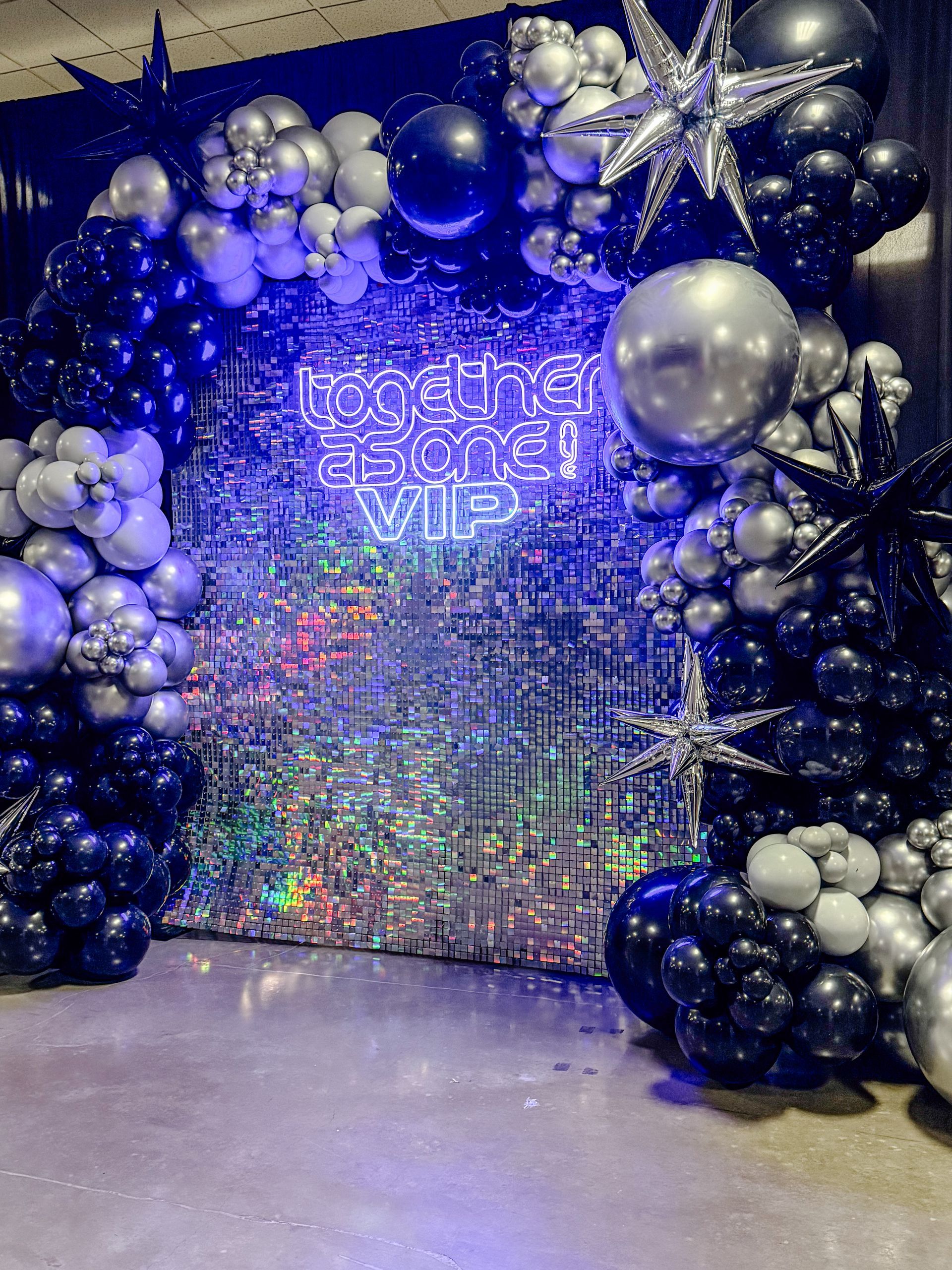 A wall covered in balloons and a neon sign.