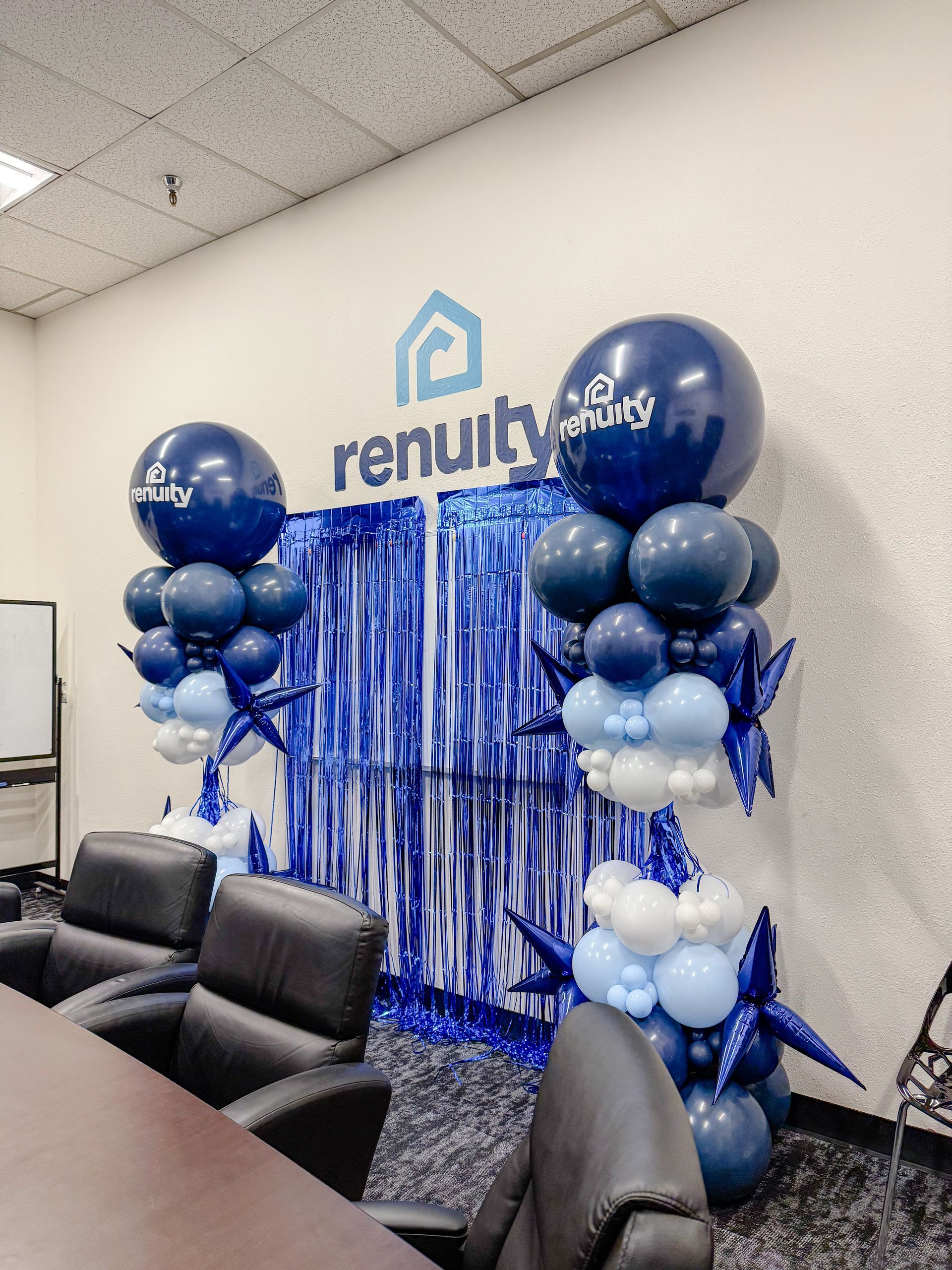 Blue and white balloon decorations in a conference room with a Renuity logo backdrop.