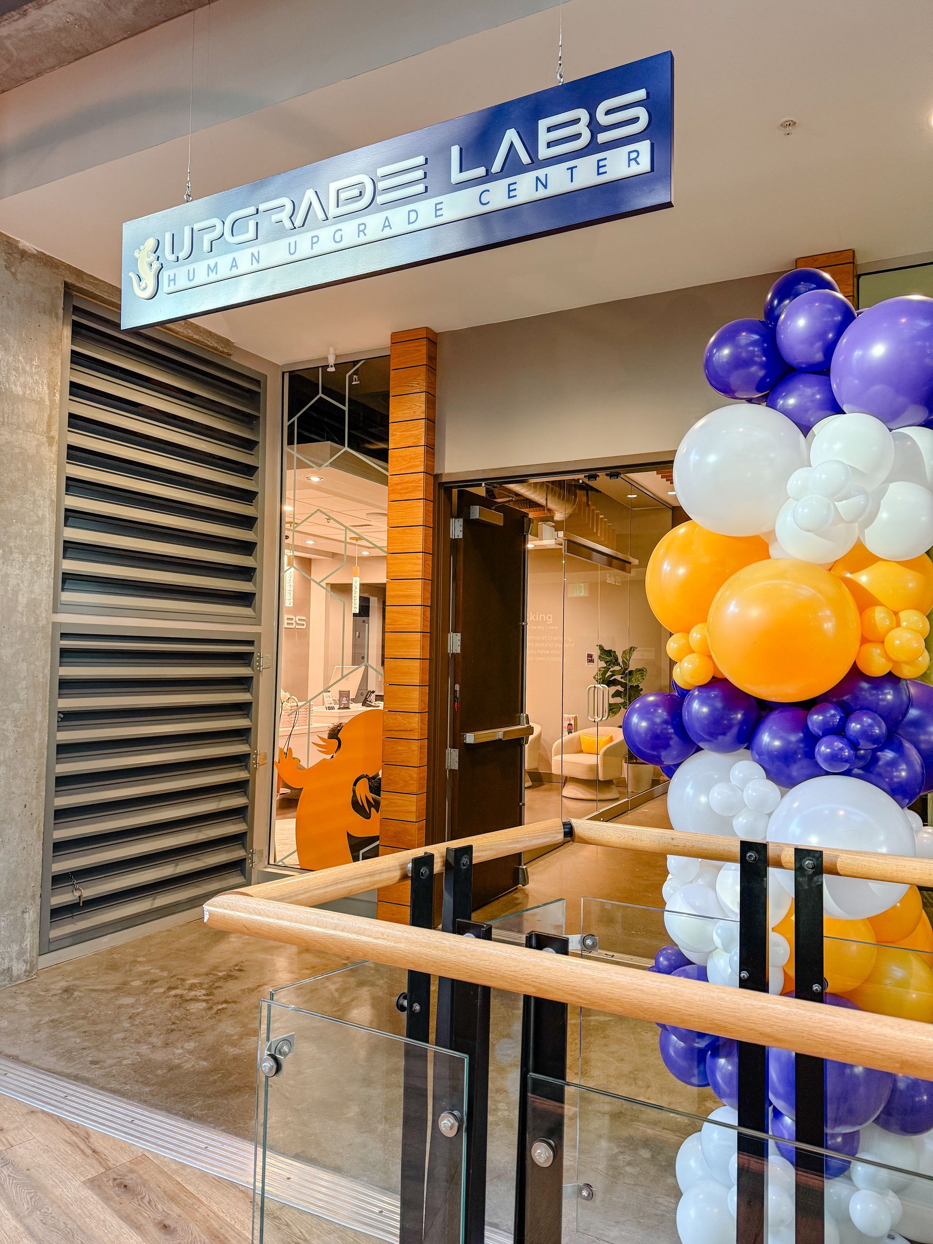 A bunch of balloons are hanging from the ceiling of a building.
