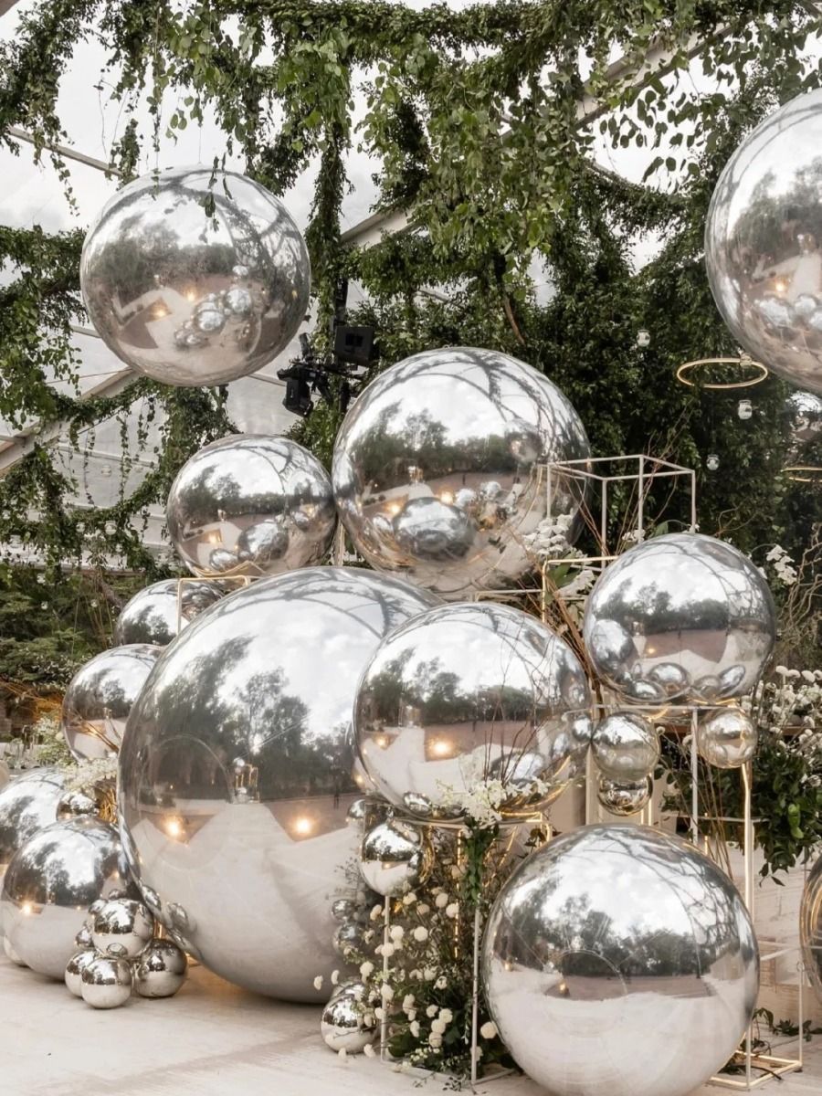 Silver mirrored spheres amidst greenery and white flowers.