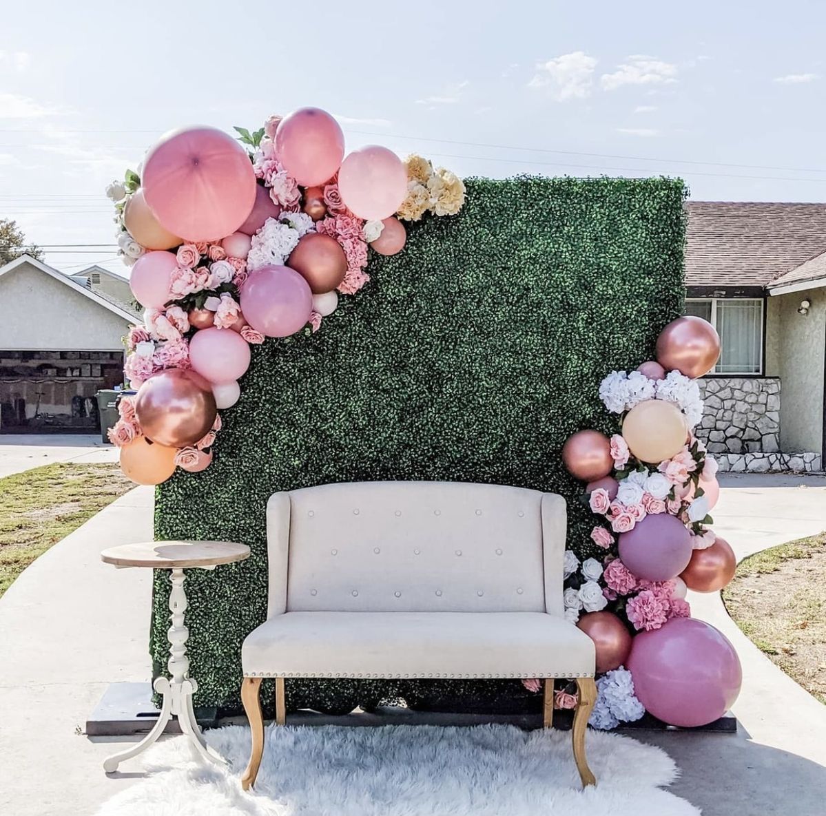 A couch is sitting in front of a wall decorated with balloons and flowers.