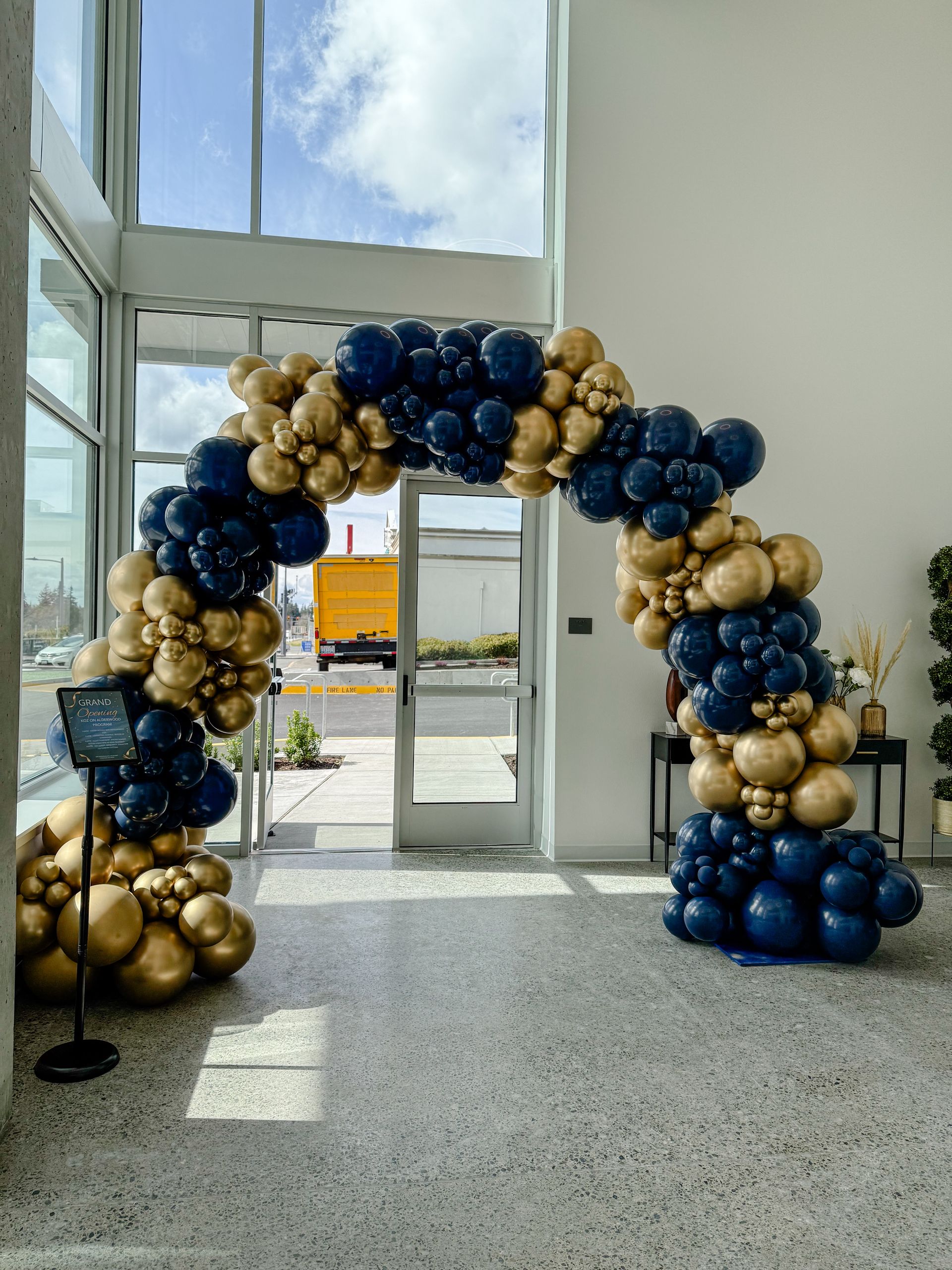 Archway of gold and navy blue balloons framing an open doorway.