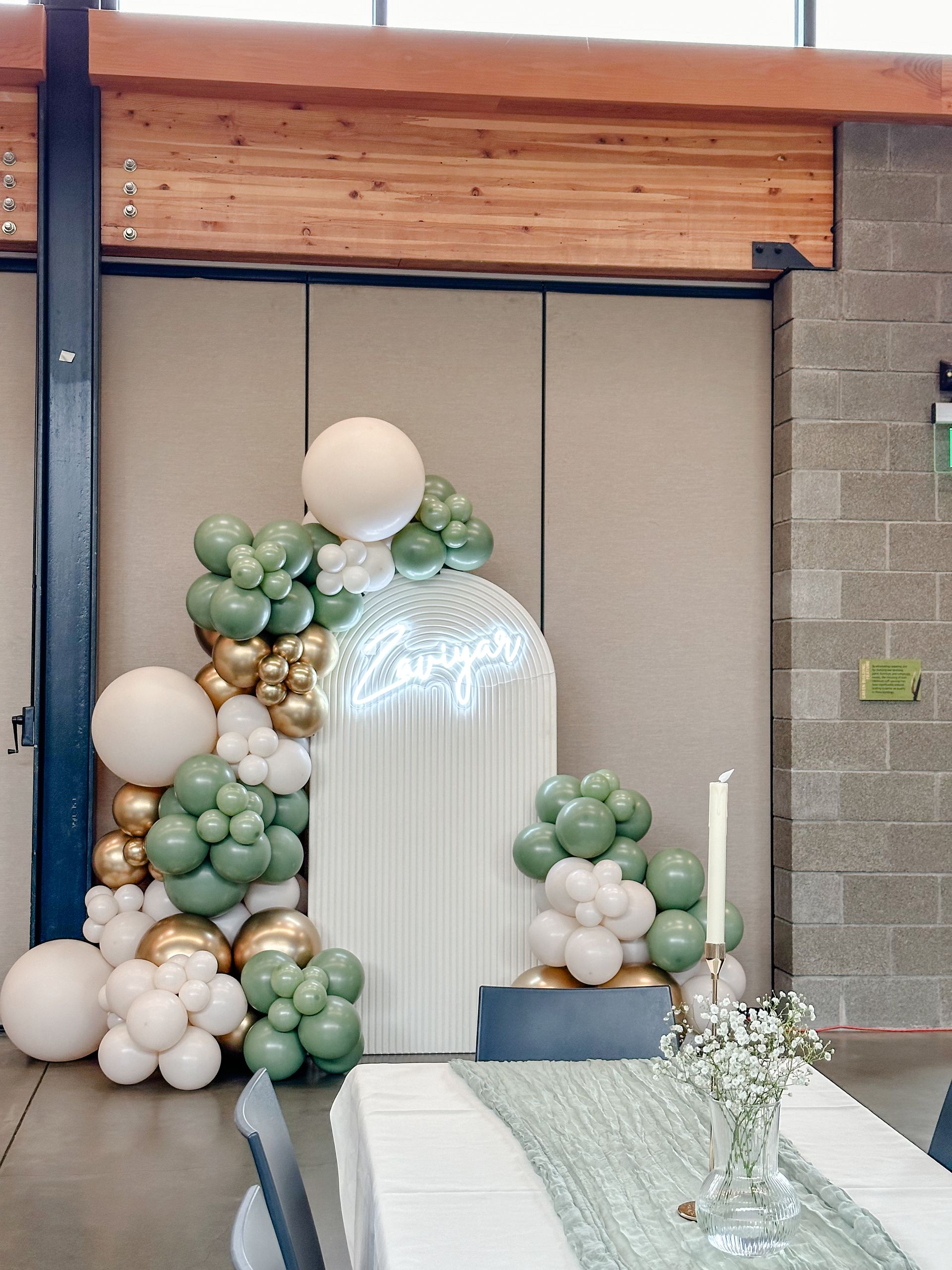 A room filled with balloons and a table with a vase of flowers on it.