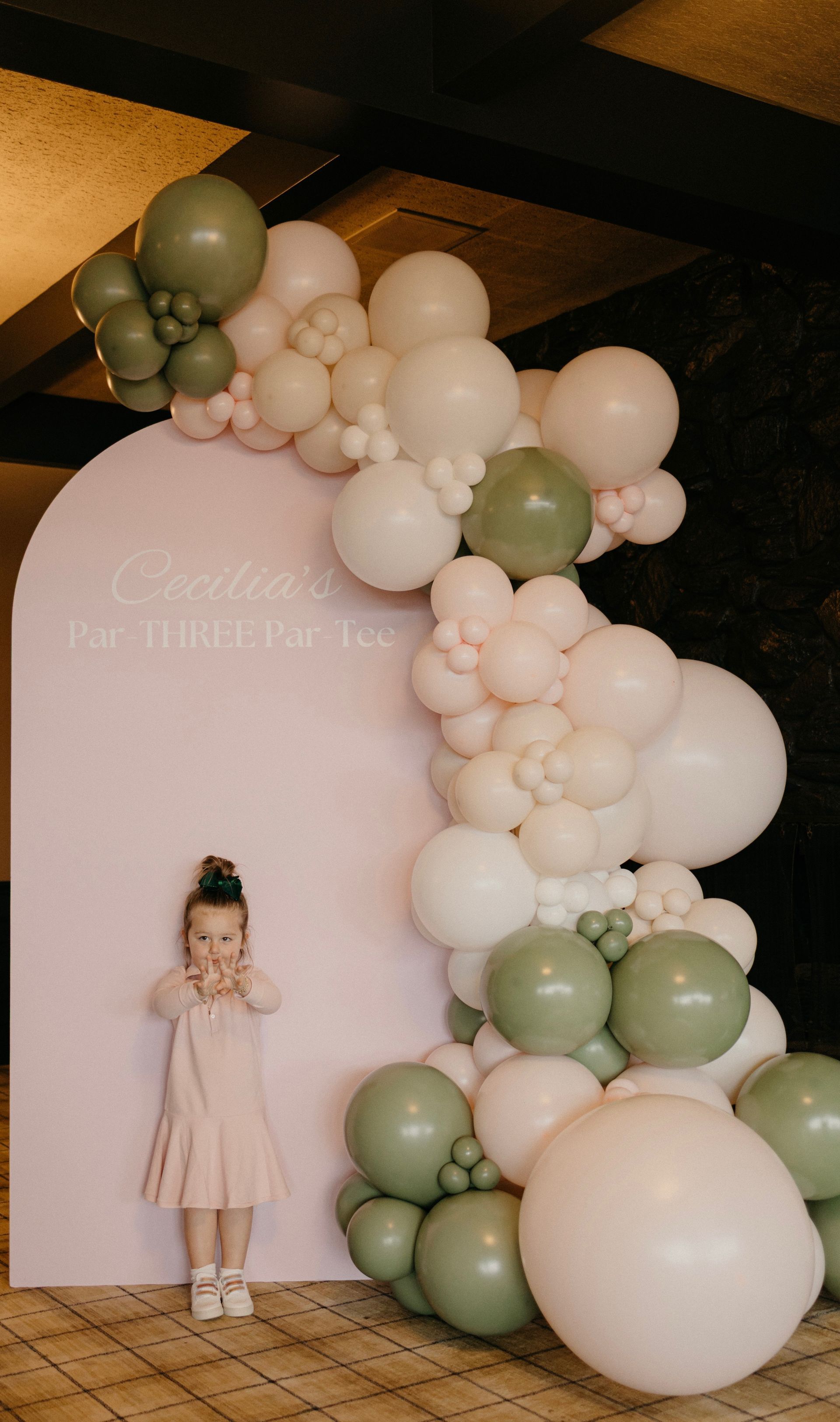 A white wall decorated with orange and white balloons and the letter t