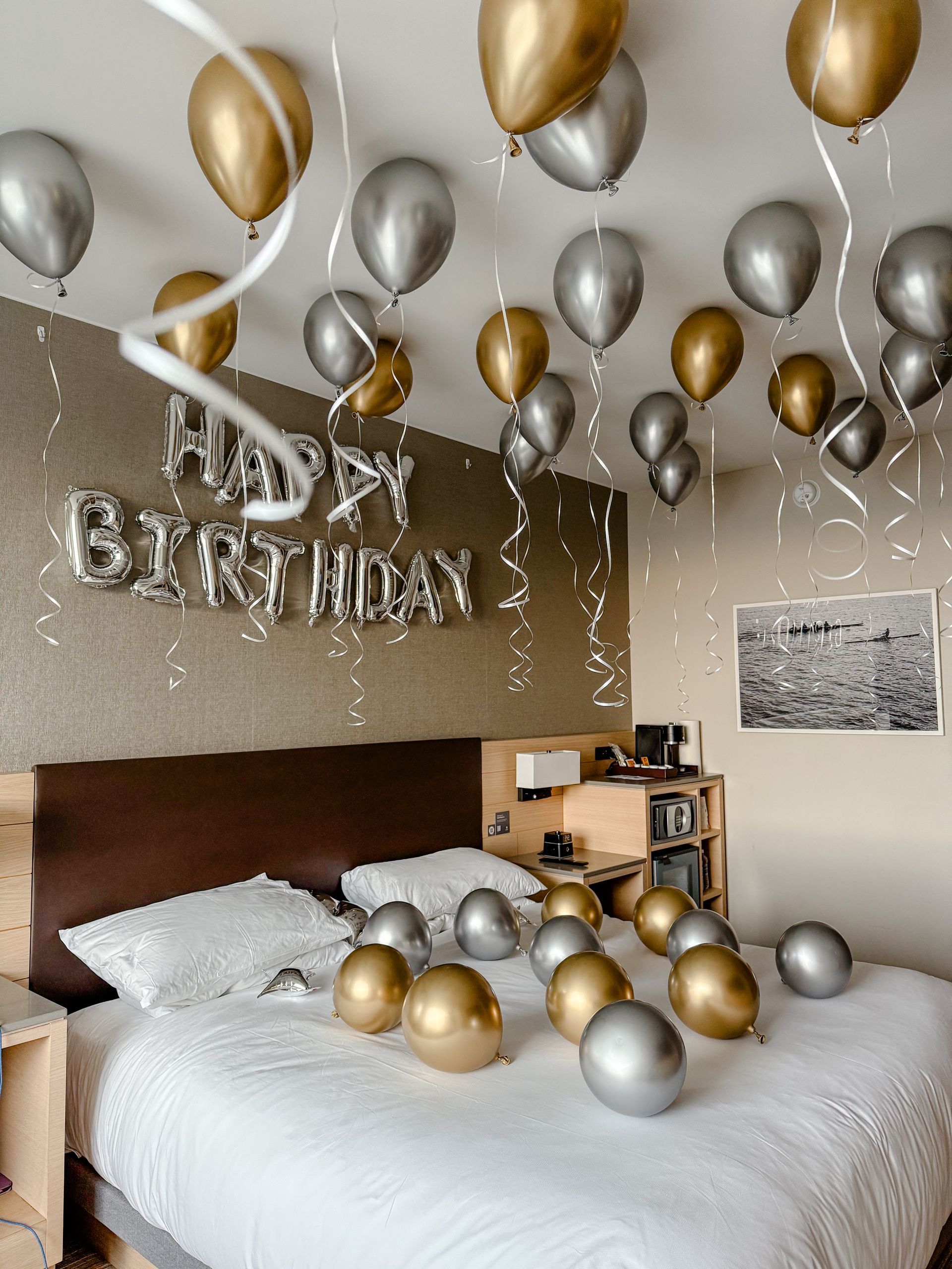 A bedroom decorated for a birthday with balloons hanging from the ceiling