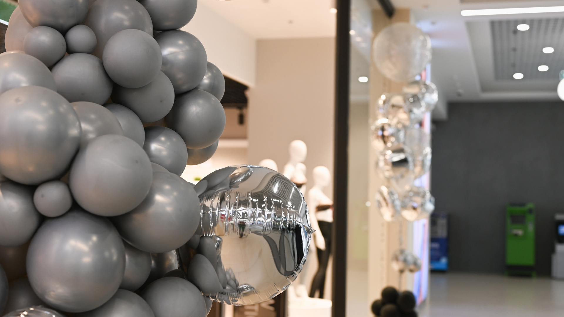 A bunch of balloons are hanging in a store window.