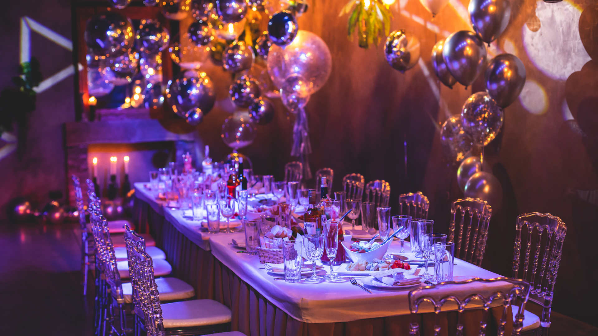 A long table is set for a party with balloons and candles.