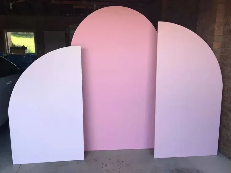 A pink and white arch is sitting in a garage.