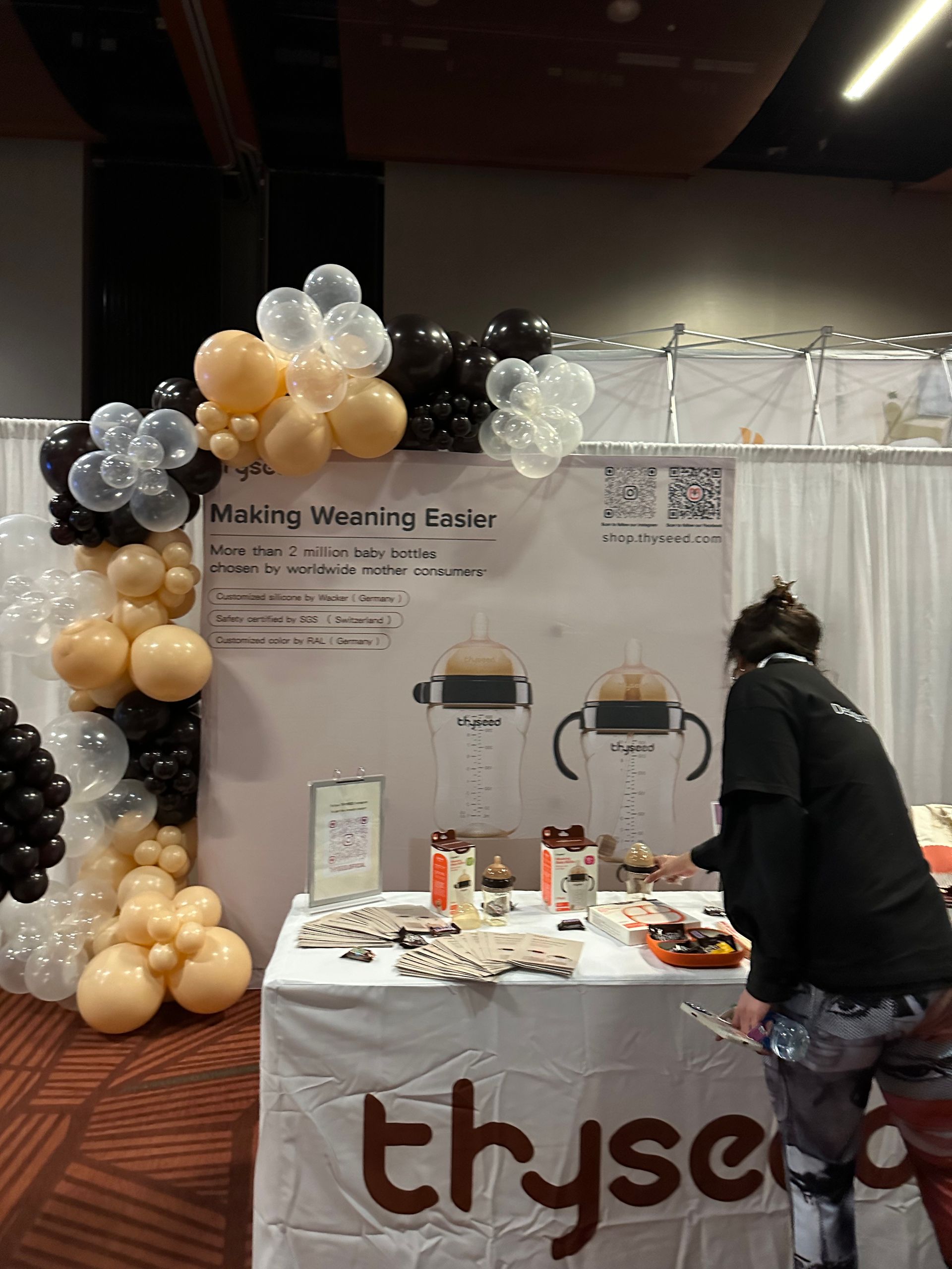 A woman is standing in front of a table with balloons on it.