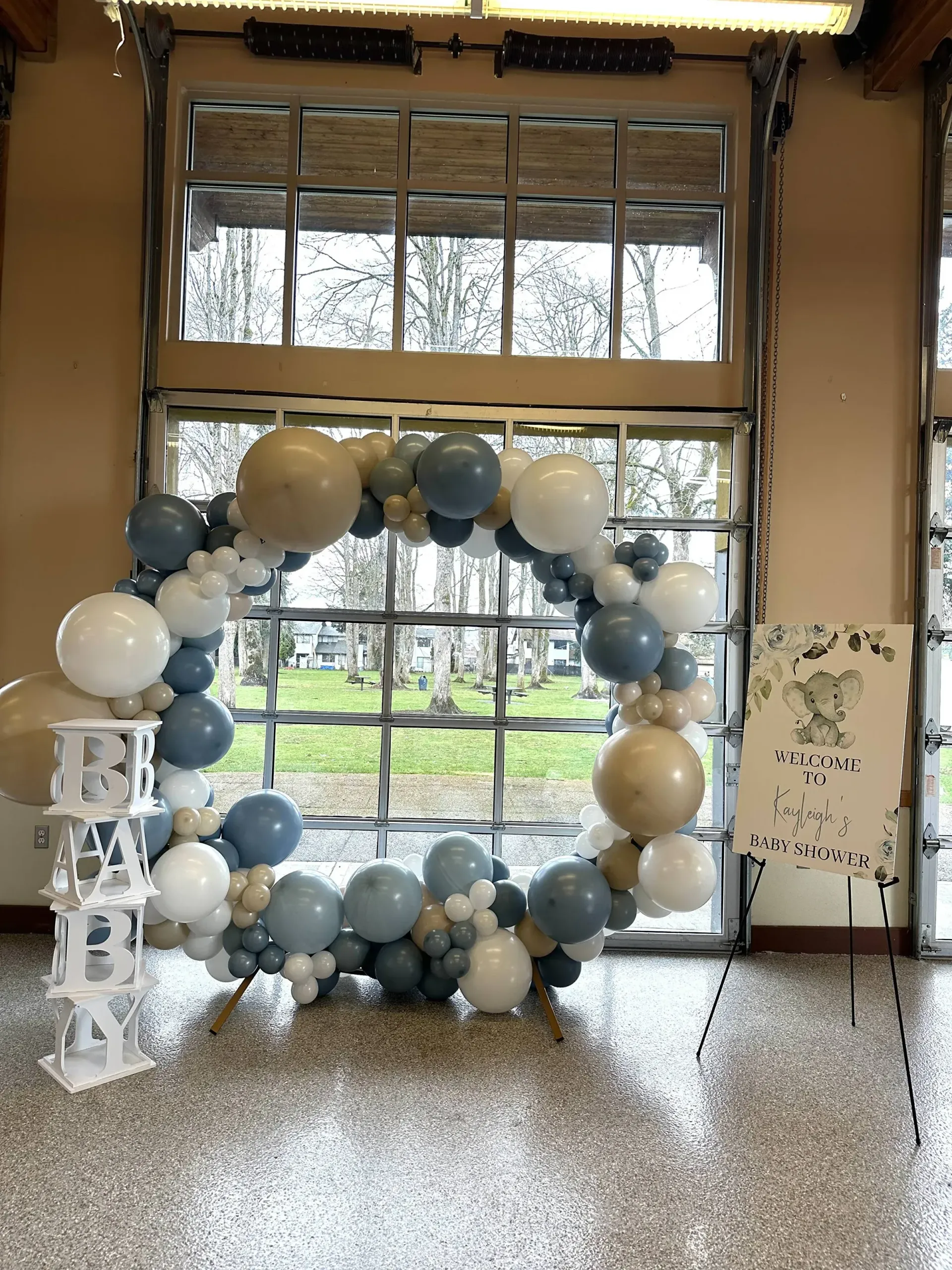 A room filled with balloons and a sign in front of a window.