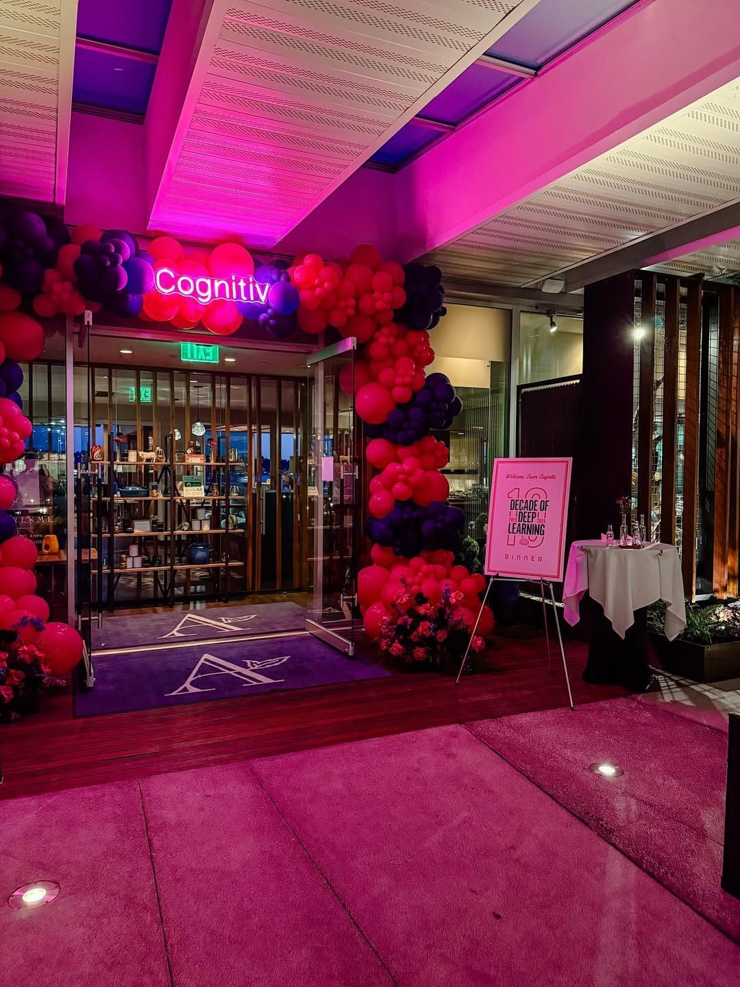 Entrance decorated for an event with pink and dark blue balloons, under a