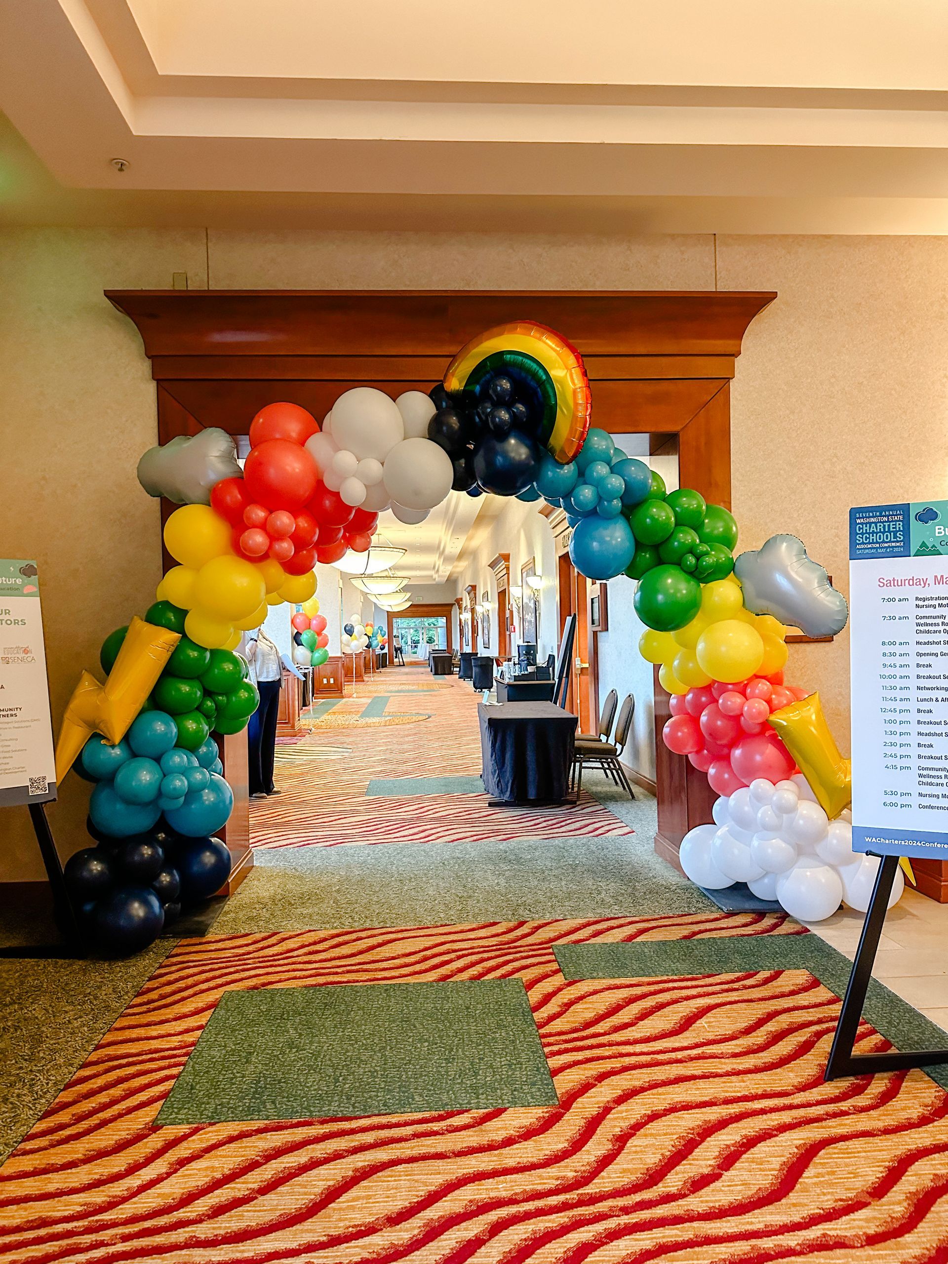 A hallway decorated with balloons and a rainbow arch.