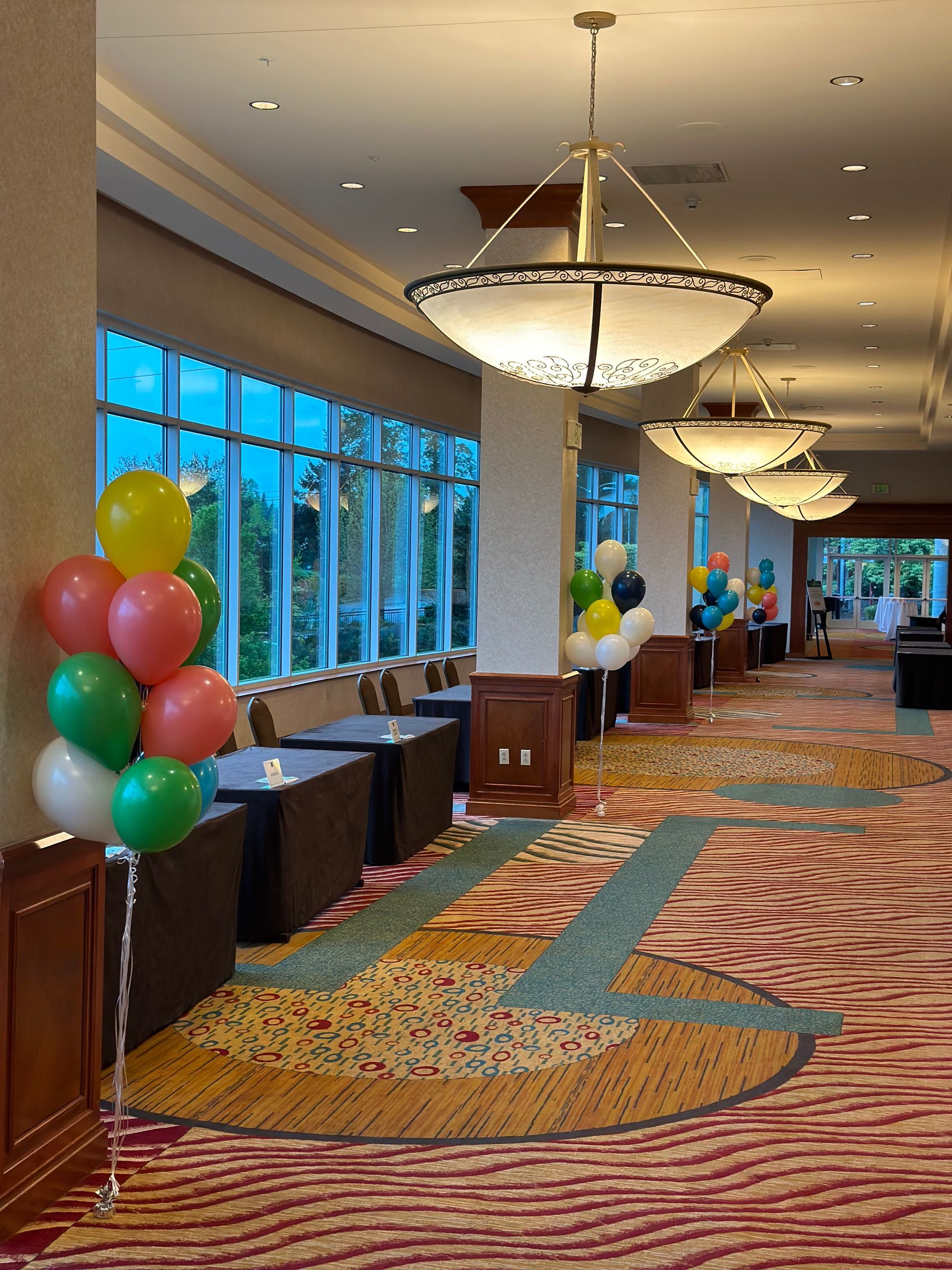 A hallway filled with tables and chairs and balloons