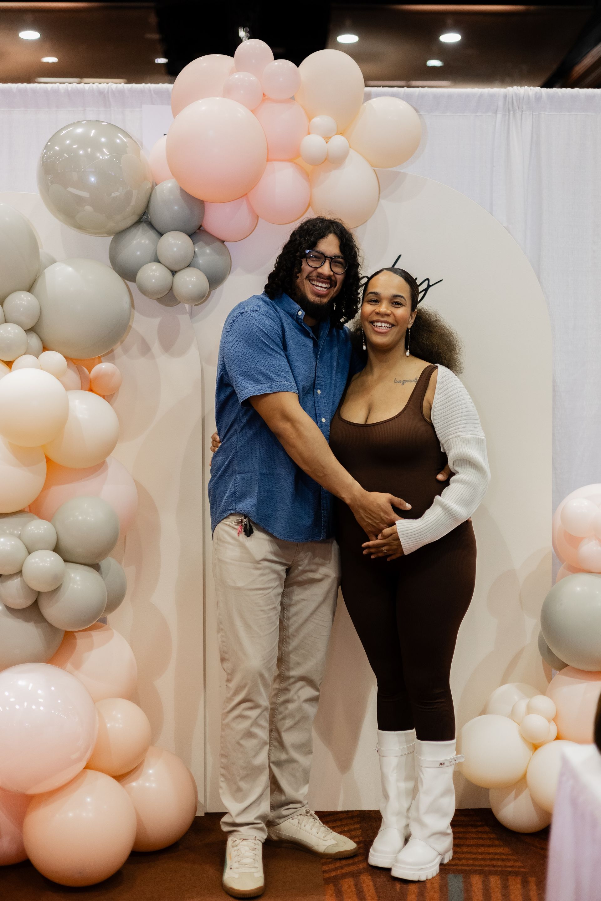 A man and a woman are standing next to each other in front of balloons.