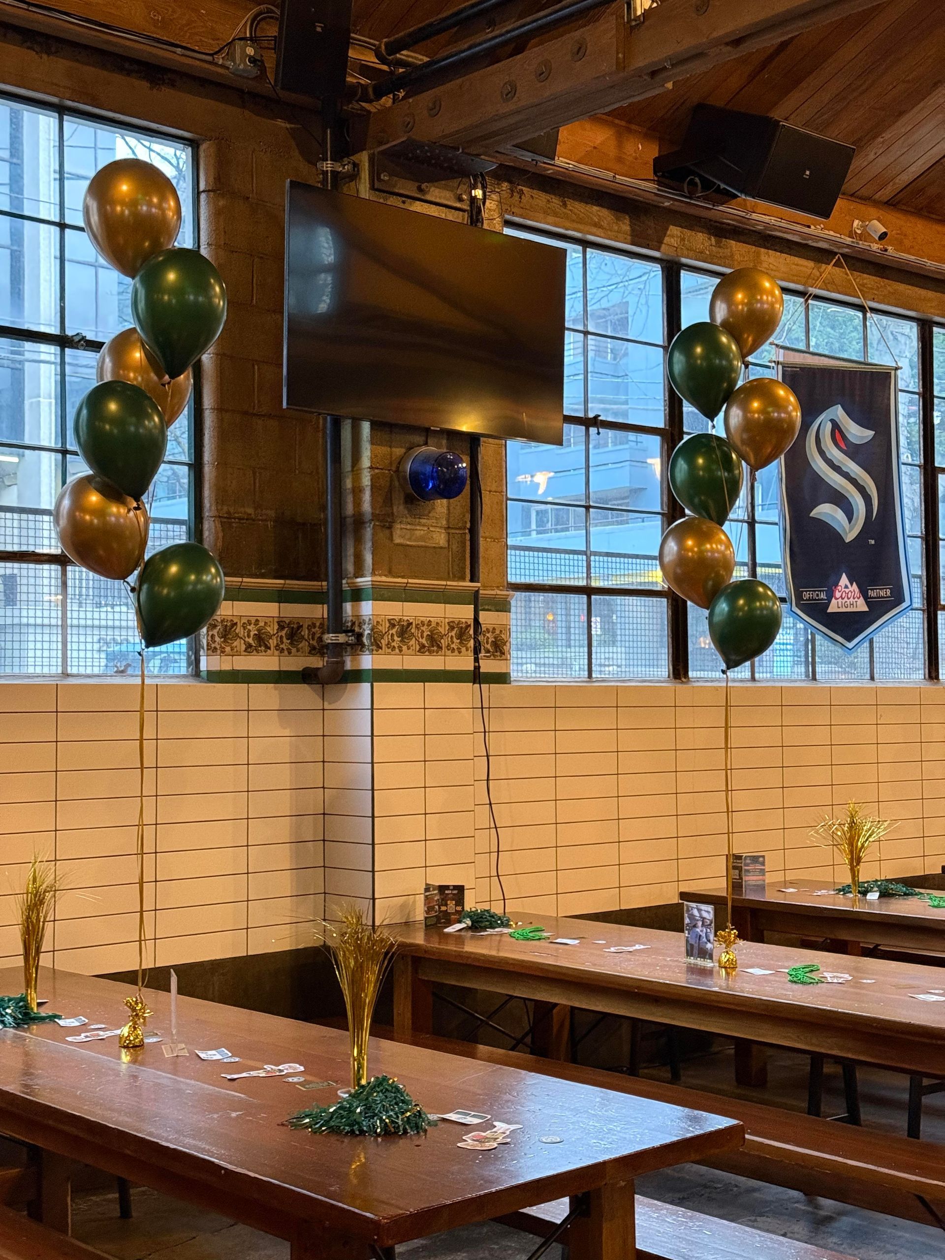 A restaurant with tables and benches and balloons hanging from the ceiling.