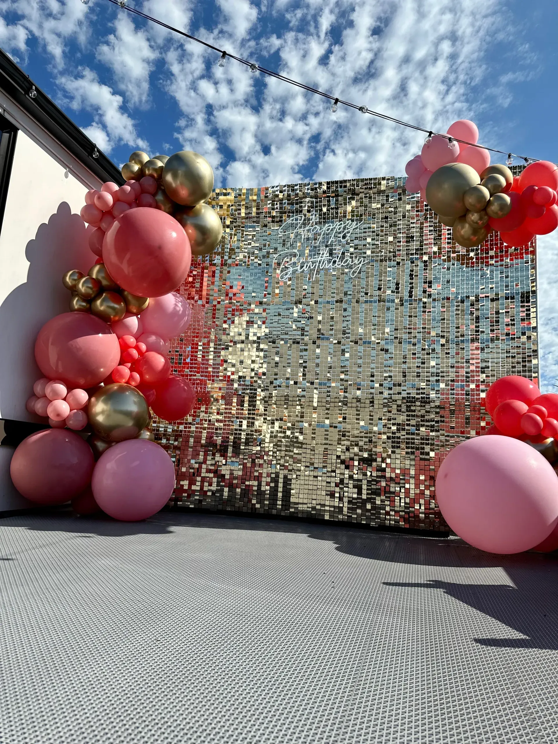 A bunch of pink and gold balloons are sitting in front of a wall.