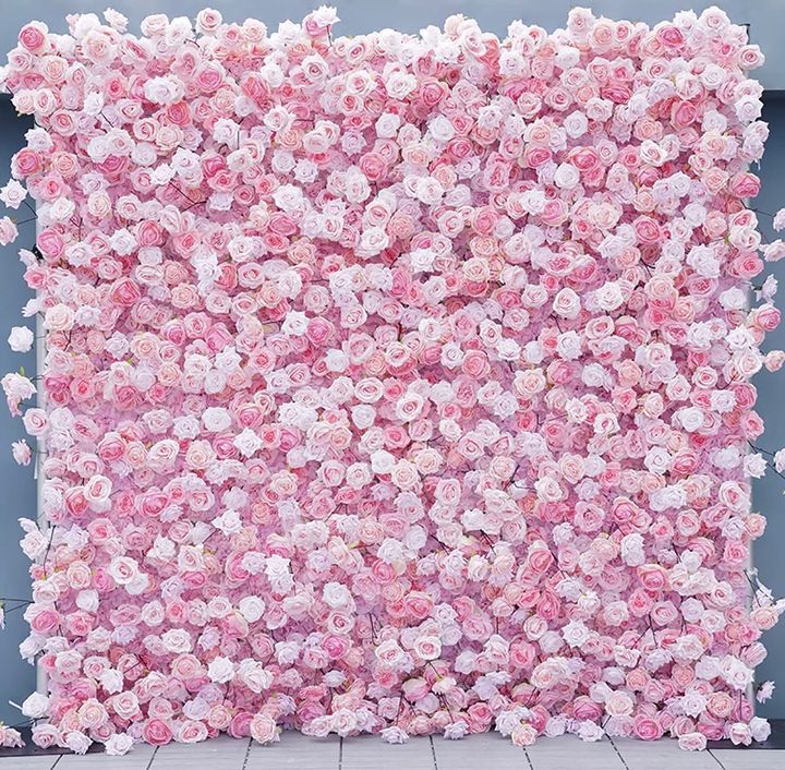A wall of pink and white flowers on a tiled floor.
