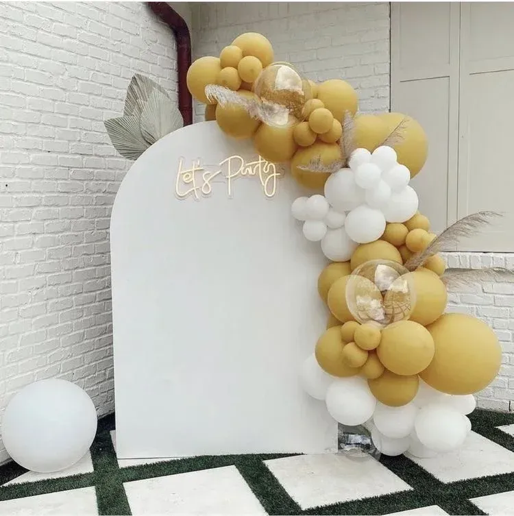 A white wall with yellow and white balloons and a neon sign that says party
