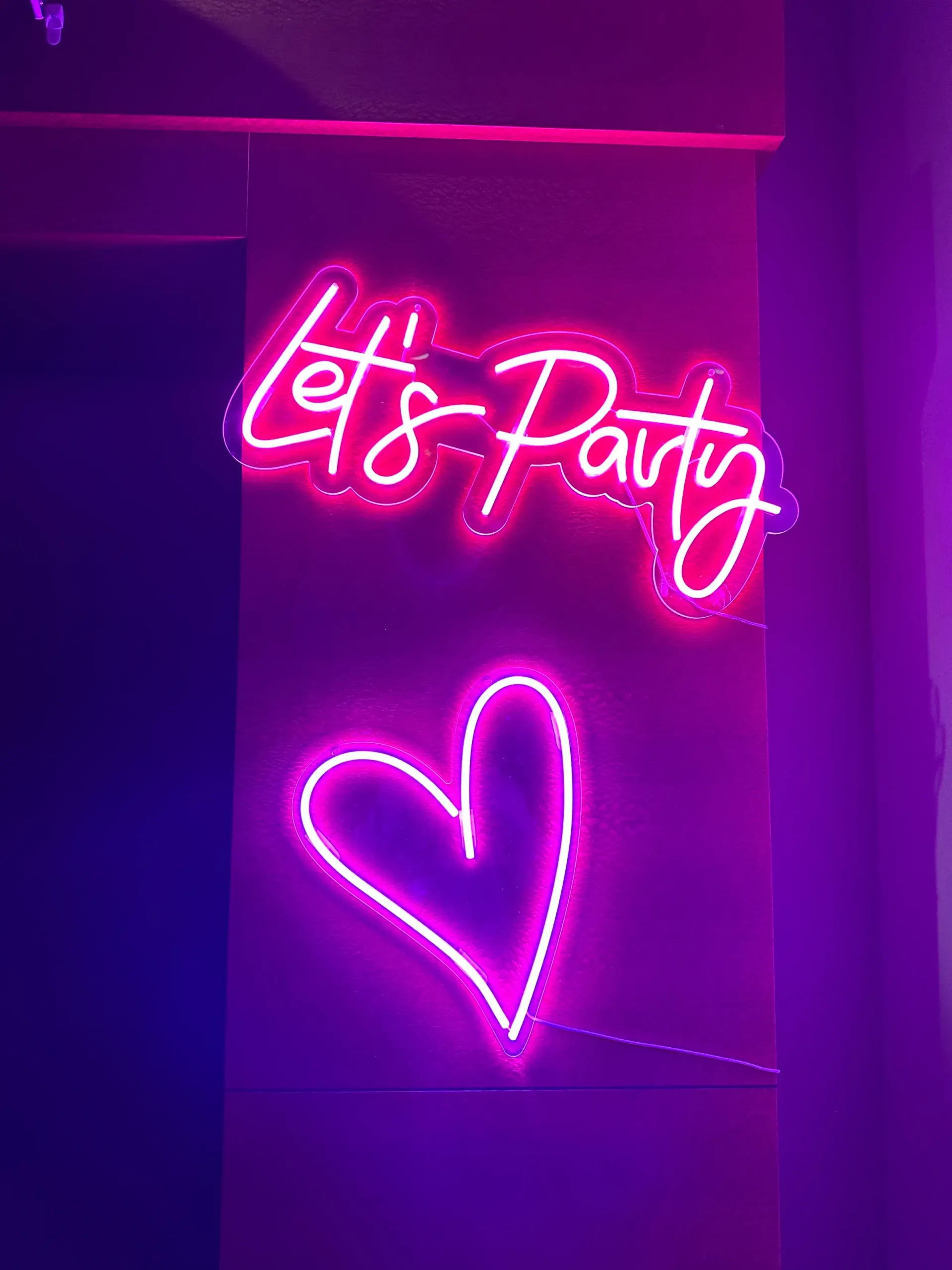 A neon sign that says `` let 's party '' and a neon heart.