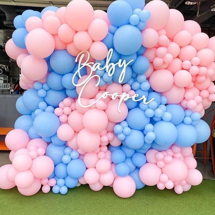 A wall of pink and blue balloons with the name baby cooper on it