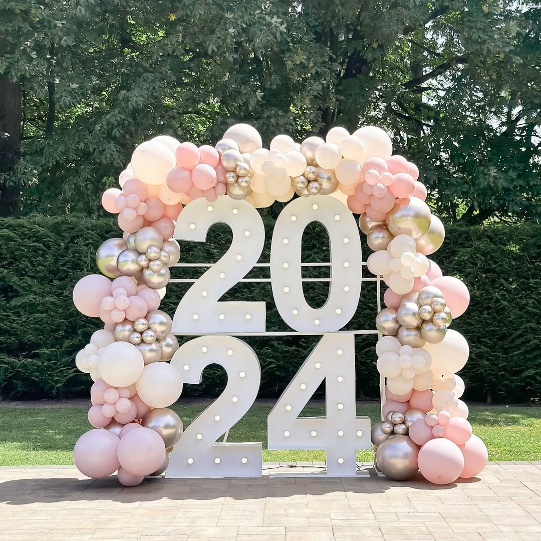 A large white sign with the number 20 and 24 surrounded by pink and gold balloons.