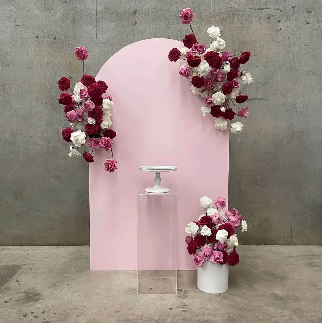 A pink backdrop with flowers and a cake stand.