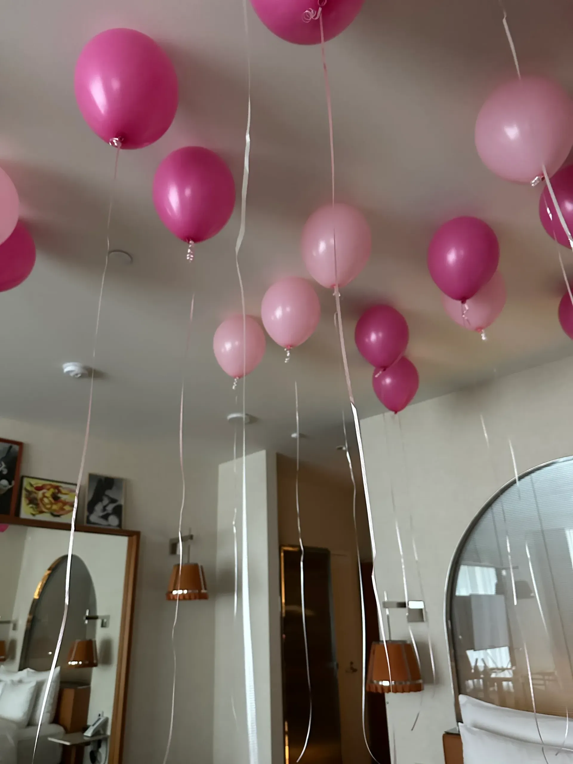 A bunch of pink balloons hanging from the ceiling