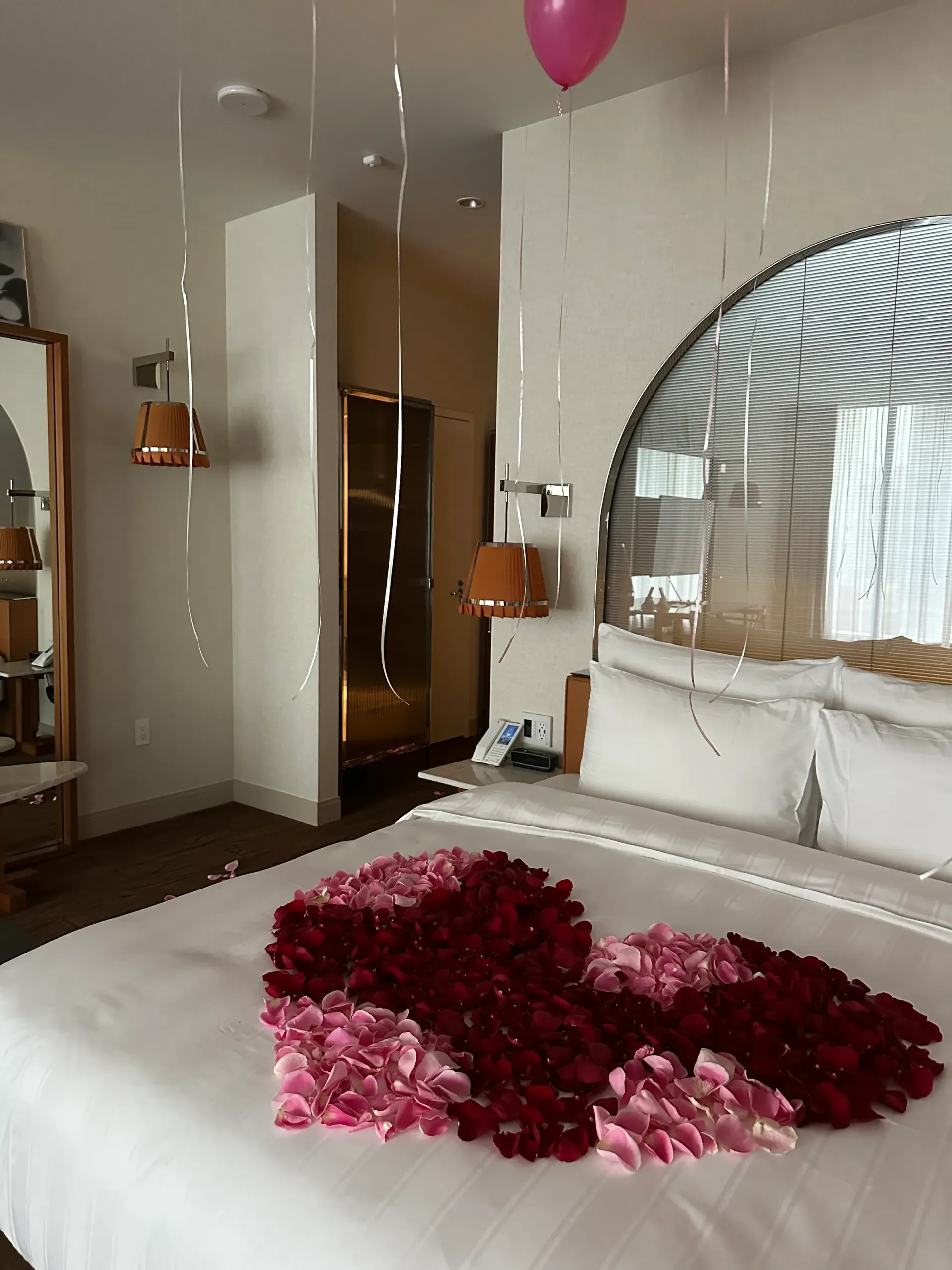 A hotel room with a bed decorated with flowers and balloons