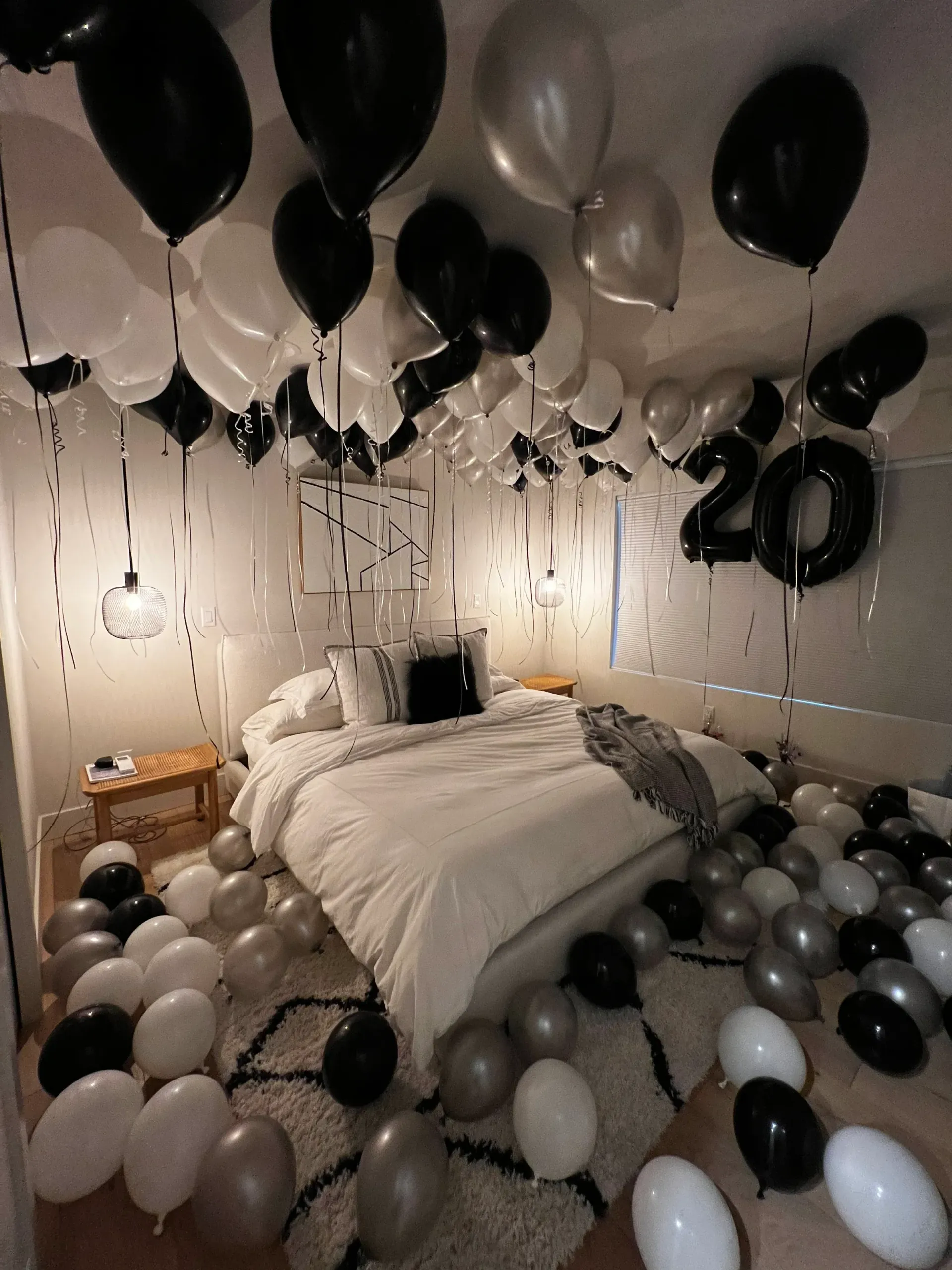A bedroom decorated with black and white balloons and a bed.