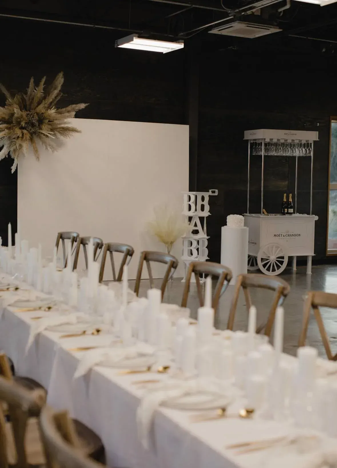 A long table set for a wedding reception with a popcorn cart in the background.