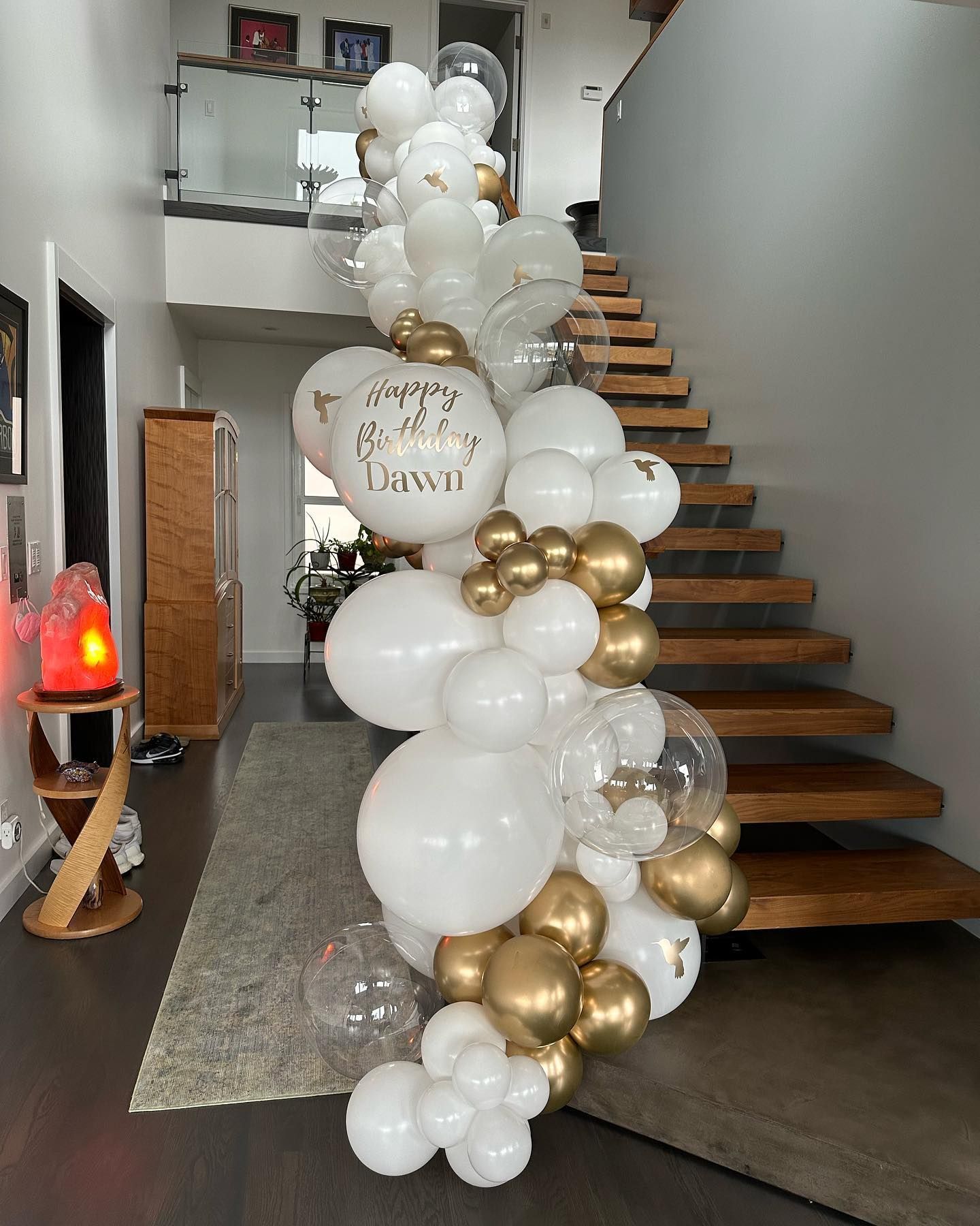 A staircase is decorated with white and gold balloons.
