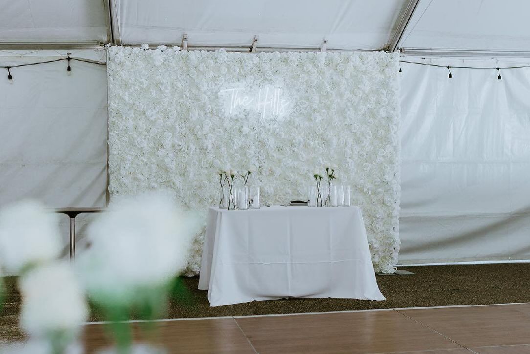 There is a table in front of a white flower wall.