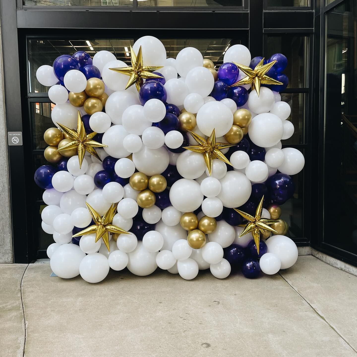 A wall of blue and white balloons with gold stars