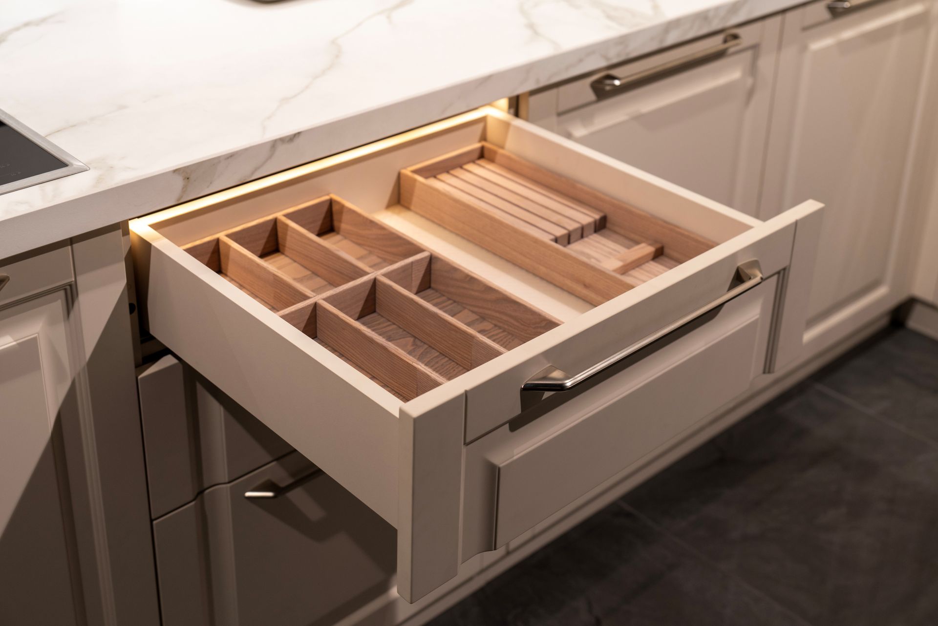 Open kitchen drawer with wooden utensil organizer.