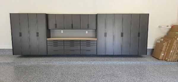 Gray garage cabinets and storage drawers along a wall in a carpeted room